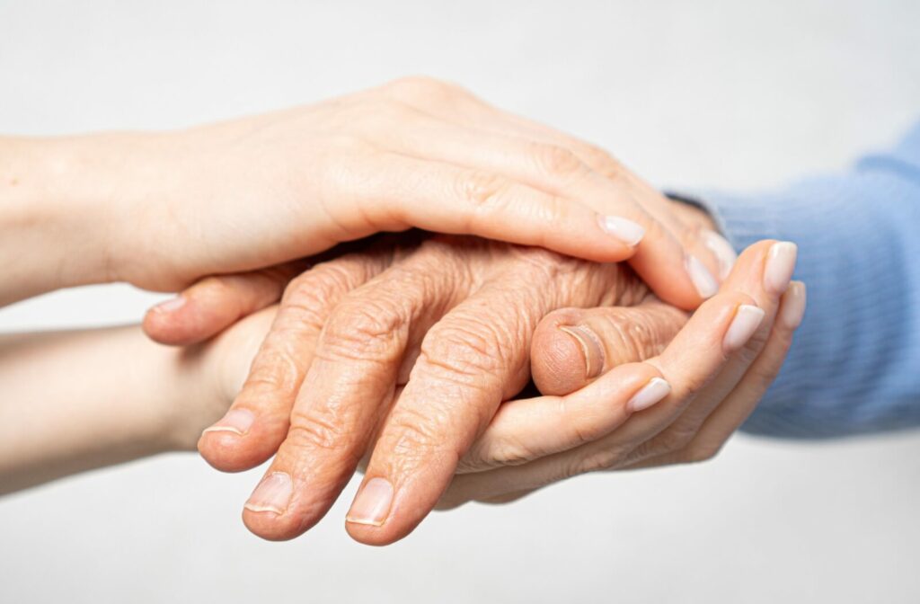 Close-up of a young person's hands holding an older person's wrinkled hand.