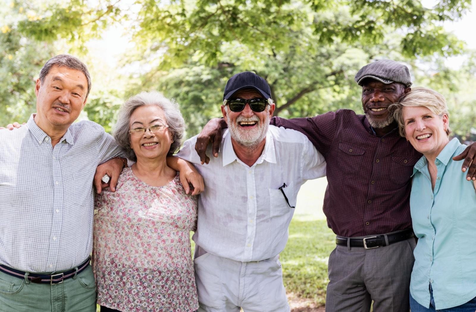 A group of senior friends in personal care smile at the camera.
