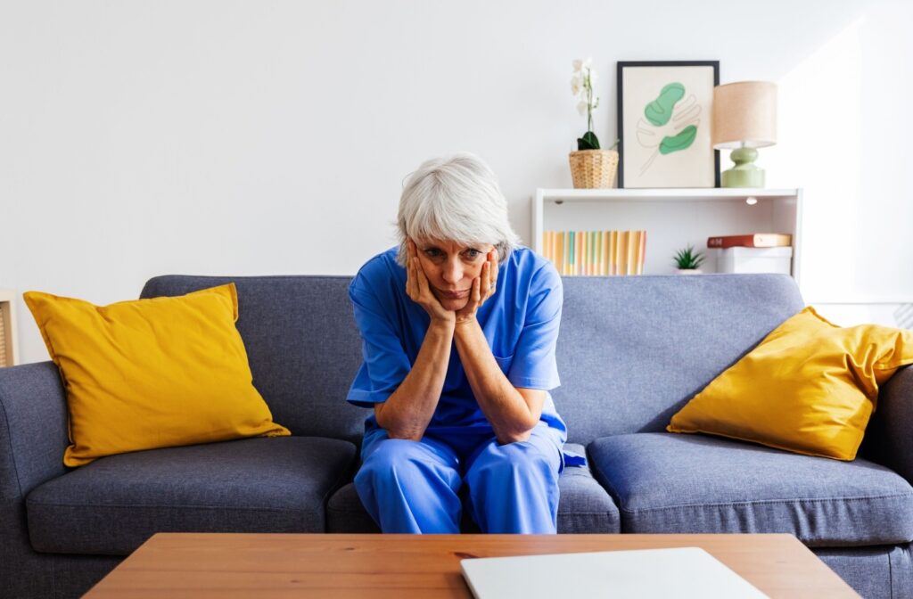 A caregiving family member sits on their sofa, looking stressed.