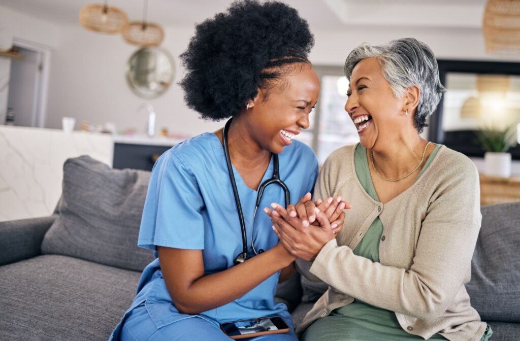 An assisted living caregiver and a resident laugh together and embrace